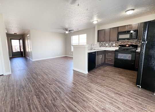 A kitchen with black appliances and wooden floors.