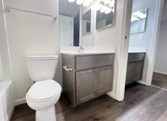a bathroom with a toilet and a sink and a mirror  at Deercross Apartments, Ohio