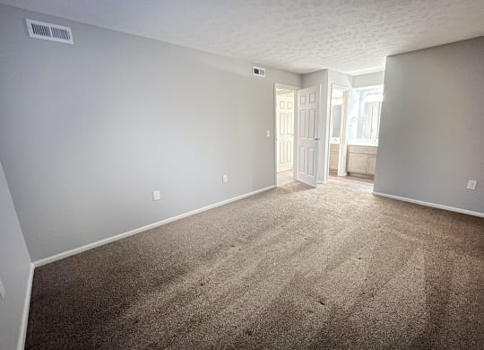an empty living room with carpet and a door to a bathroom  at Deercross Apartments, Cincinnati