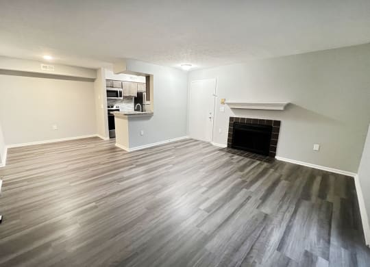 an empty living room with a fireplace and wooden floors  at Deercross Apartments, Cincinnati