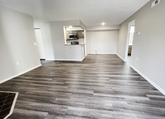 an empty living room with wood flooring and a kitchen  at Deercross Apartments, Cincinnati