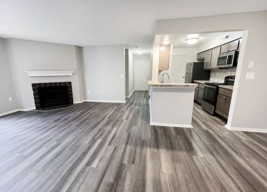 an empty living room with a fireplace and a kitchen  at Deercross Apartments, Cincinnati