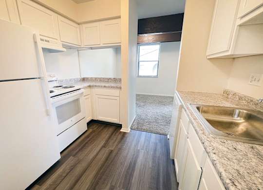 an empty kitchen with white appliances and white cabinets at Four Worlds Apartments, Ohio
