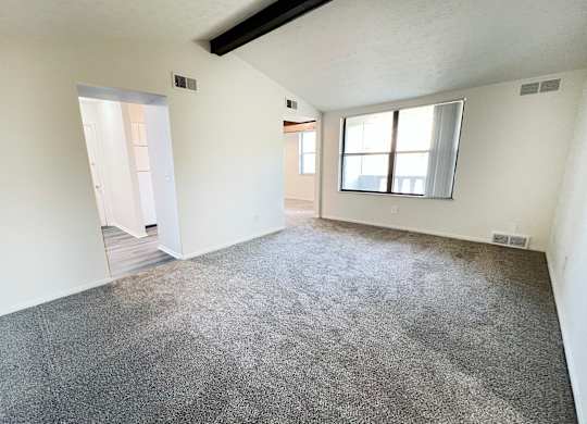 an empty living room with carpet and a window at Four Worlds Apartments, Cincinnati, 45231