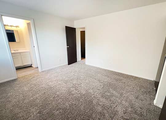 an empty living room with carpeting and a door to a bathroom at Four Worlds Apartments, Cincinnati, OH 45231