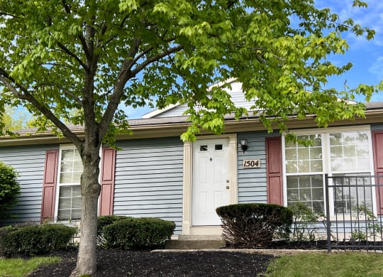 a house with a white door and red shutters and a tree in front of it  at Woodhills Apartments, West Carrollton, Ohio