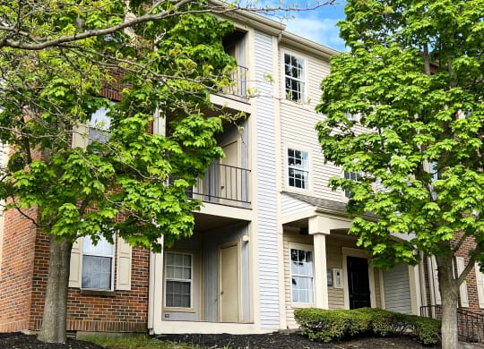 a picture of a three story apartment building with trees in front of it  at Woodhills Apartments, West Carrollton, OH, 45449