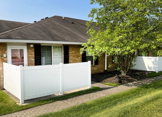 a white privacy fence in front of a brick house  at Wyndemere Apartments, Franklin, Ohio