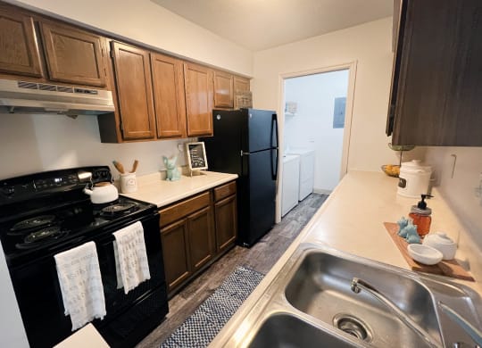 a kitchen with a black refrigerator freezer next to a stove top oven  at Steeplechase Apartments, Ohio, 45140