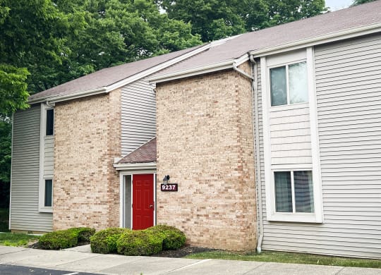 a brick building with a red door and white siding  at Hunter's Creek Apartments, Cincinnati, 45242