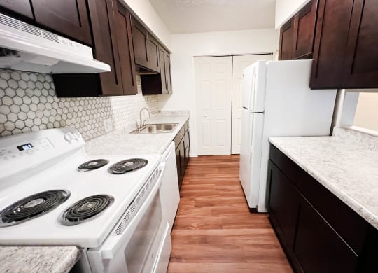 a kitchen with white appliances and brown cabinets  at Concord Woods Apartments, Ohio