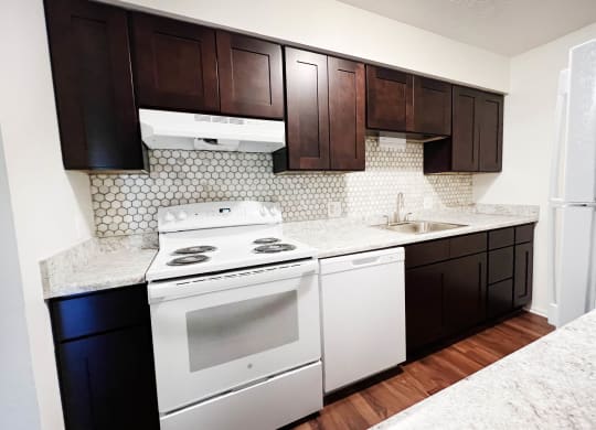 a kitchen with white appliances and dark wood cabinets  at Concord Woods Apartments, Milford, OH
