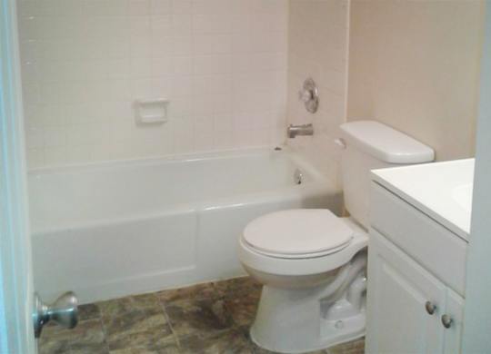 A white toilet sits next to a white cabinet in a bathroom.