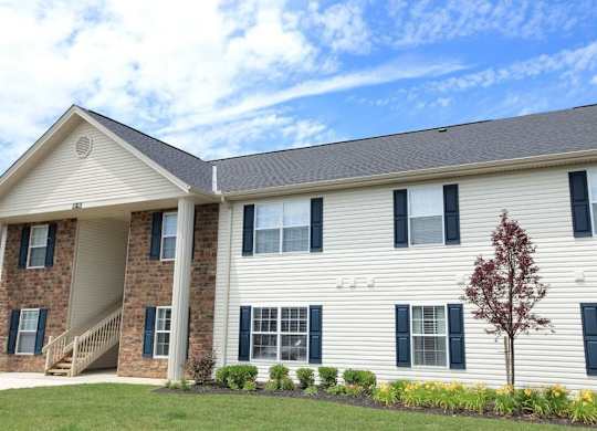 A two-story house with a red tree in front.