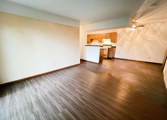 an empty living room with wood floors and a kitchen at Forest Creek Apartments, Middletown, Ohio