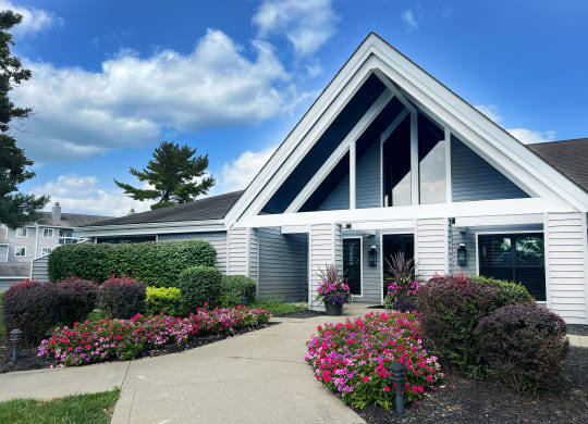 the front of a white house with a sidewalk and colorful flowers at Deercross Apartments, Cincinnati