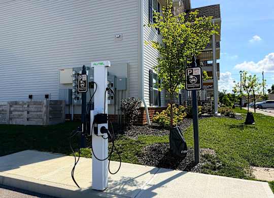A parking sign is next to a charging station.