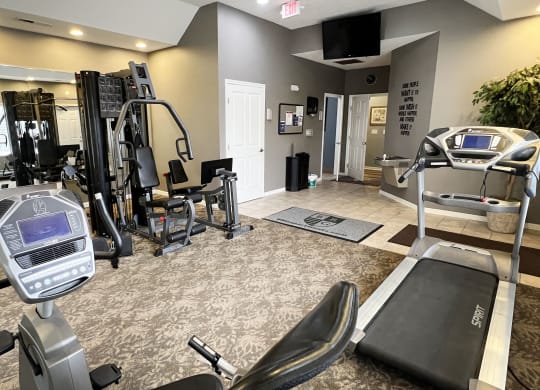 a gym with exercise equipment and a tv on the wall