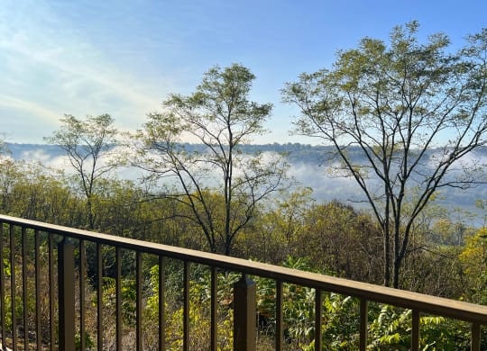 a balcony with a view of trees and fog in the distance at Indian Lookout Apartments, Cincinnati