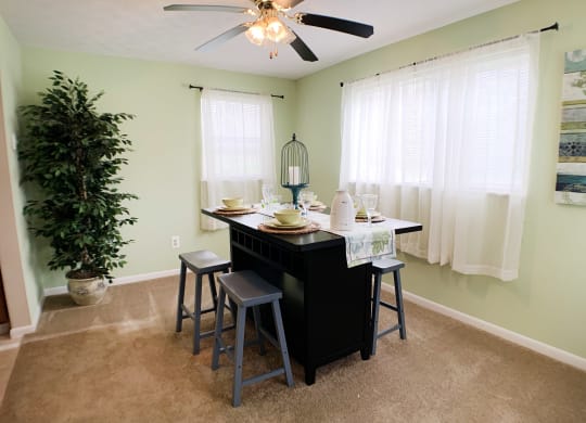 an island with stools in a dining room with a ceiling fan at The Vinings Apartments, Cincinnati, OH