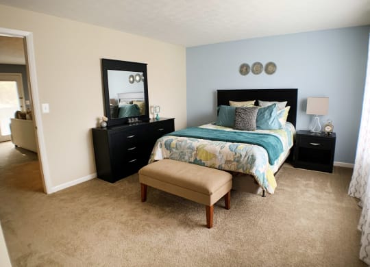 a bedroom with a bed and a dresser and a window at The Vinings Apartments, Cincinnati, 45245
