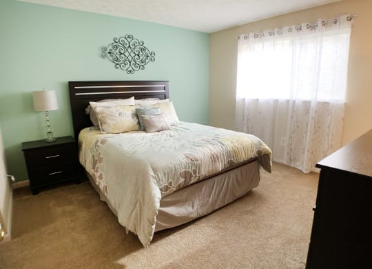 a bedroom with a bed and a dresser and a window at The Vinings Apartments, Cincinnati, OH, 45245