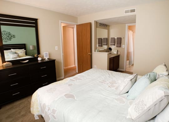 a bedroom with a large white bed and a mirror at The Vinings Apartments, Cincinnati