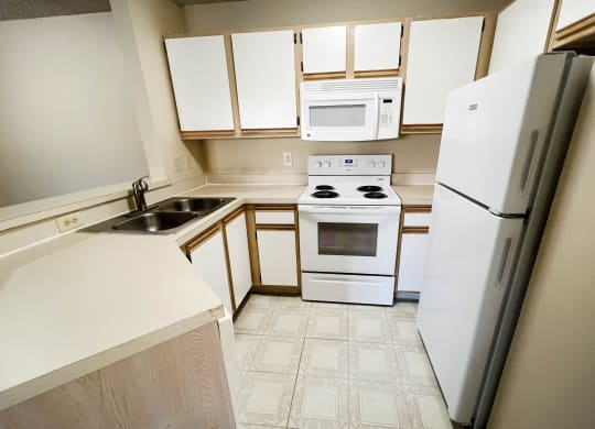 an empty kitchen with white appliances and white cabinets at Eagle Crest Apartments, Galloway, OH