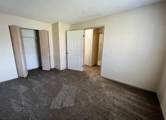 an empty living room with carpet and a door to a closet at Eagle Crest Apartments, Ohio, 43119