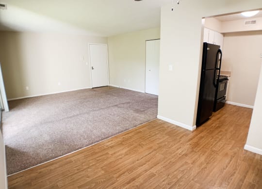 an empty living room with wood flooring and a black refrigerator  at Hunter's Creek Apartments, Cincinnati, OH