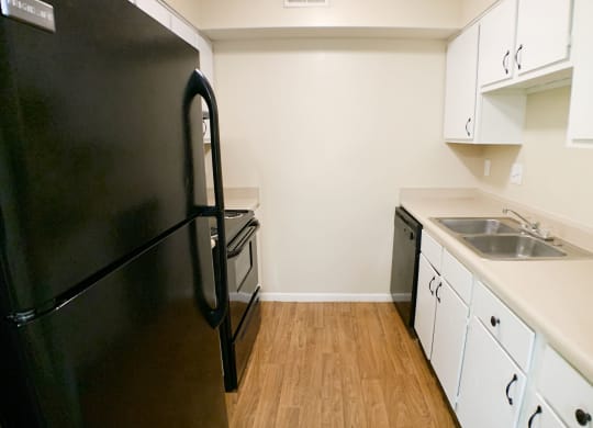 a kitchen with white cabinets and a black refrigerator at Hunter's Creek Apartments, OH