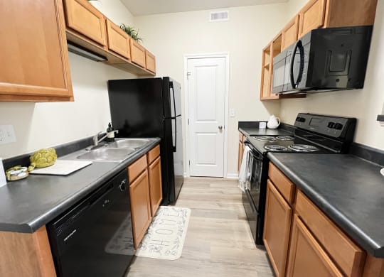 an empty kitchen with black appliances and wooden cabinets at Residences at Northgate Crossing, Ohio, 43235