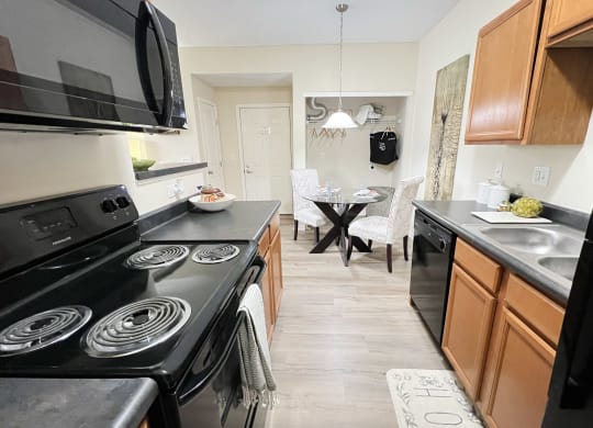 a kitchen and dining room with black appliances and wooden cabinets at Residences at Northgate Crossing, Ohio, 43235