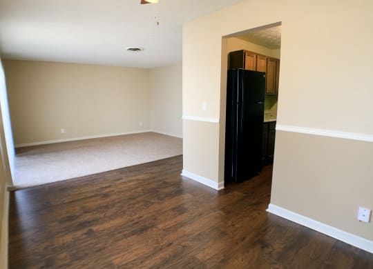an empty living room with wood floors and a black refrigerator  at Timber Ridge Apartments, Cincinnati