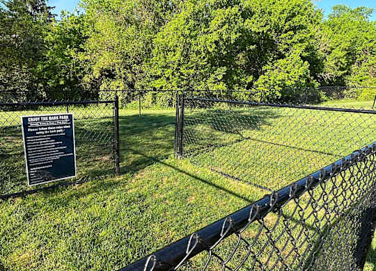 A sign is posted on a fence in a grassy area.
