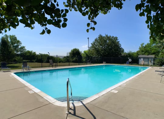 a swimming pool with chairs and a fence around it  at Knobs Pointe Apartments, New Albany