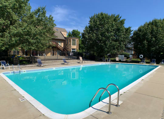 a swimming pool with chairs around it and a house in the background  at Knobs Pointe Apartments, New Albany, Indiana