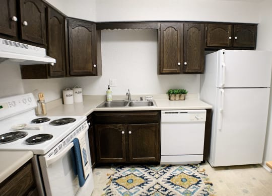 a kitchen with white appliances and brown cabinets and a white refrigerator at Knobs Pointe Apartments, New Albany, Indiana