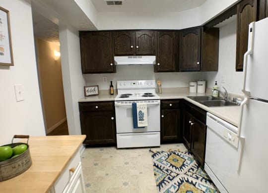 a kitchen with white appliances and dark wood cabinets at Knobs Pointe Apartments, Indiana