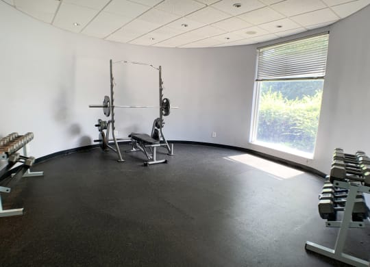 a gym with weights and a window in the corner of a room  at Knobs Pointe Apartments, New Albany, IN