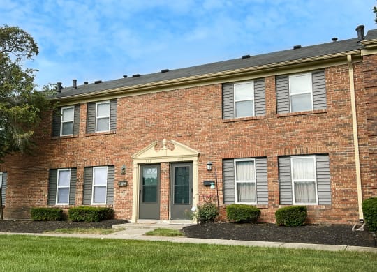 a brick building with a green door and grass at Revere Village Apartments, Centerville, Ohio
