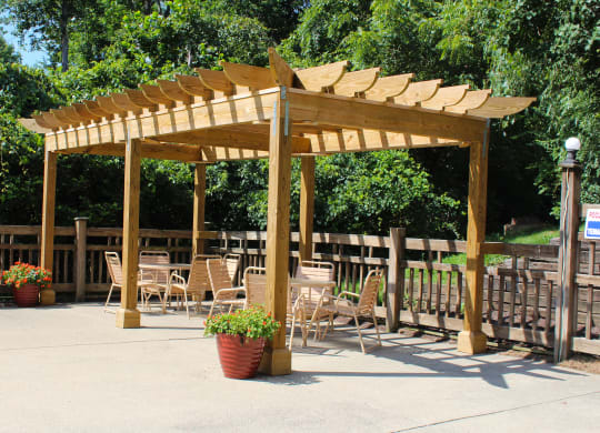 a wooden pergola with tables and chairs under it at The Vinings Apartments, Cincinnati