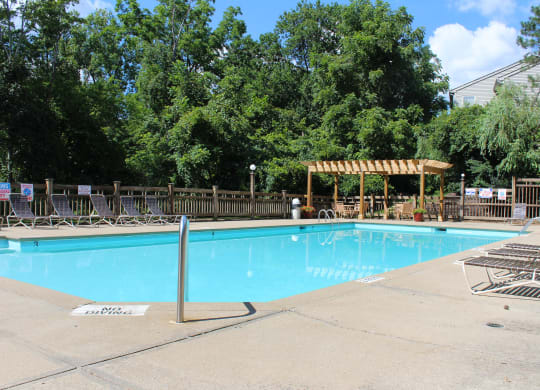 a swimming pool with chairs and a wooden fence around it at The Vinings Apartments, Cincinnati, Ohio