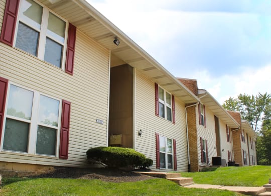 a yellow house with red window shutters and a green yard  at Timber Ridge Apartments, Cincinnati