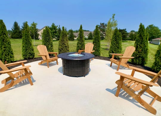 a patio with a fire pit and wooden chairs at Steeplechase Apartments, Loveland, 45140