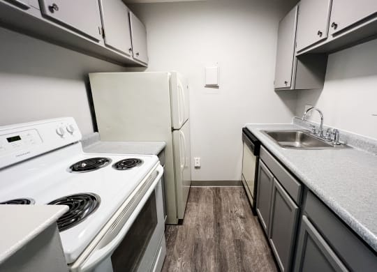 a kitchen with white appliances and gray cabinets  at Summit East - A Senior Community, Cincinnati, Ohio