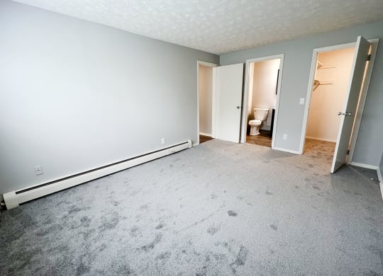 an empty bedroom with a bathroom in the background  at Summit East - A Senior Community, Cincinnati, OH, 45237