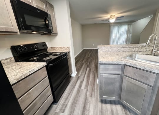 a kitchen with a black stove top oven next to a sink  at Woodhills Apartments, Ohio, 45449