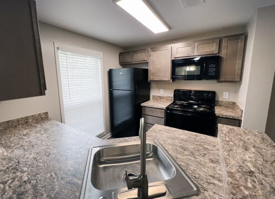 a kitchen with granite countertops and black appliances  at Woodhills Apartments, Ohio