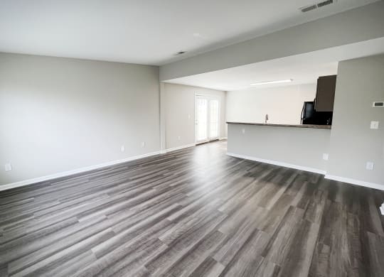 an empty living room with a kitchen in the background  at Woodhills Apartments, West Carrollton, Ohio